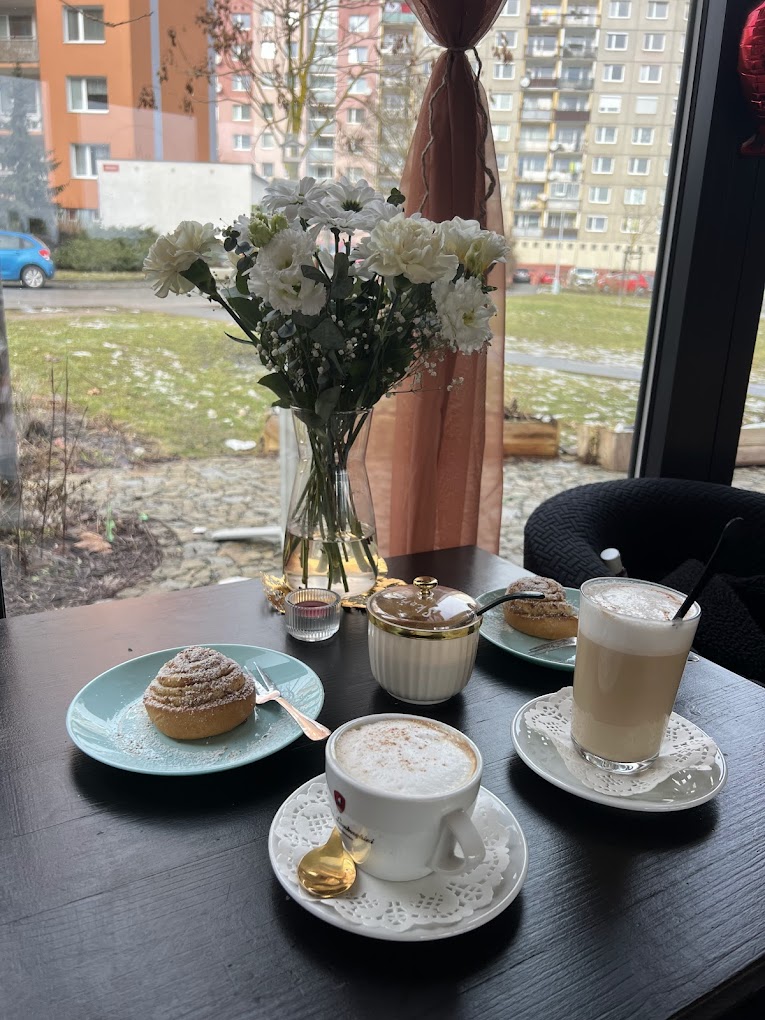 Stůl u okna Kavárny K s cappuccinem, latté a domácím zákuskem