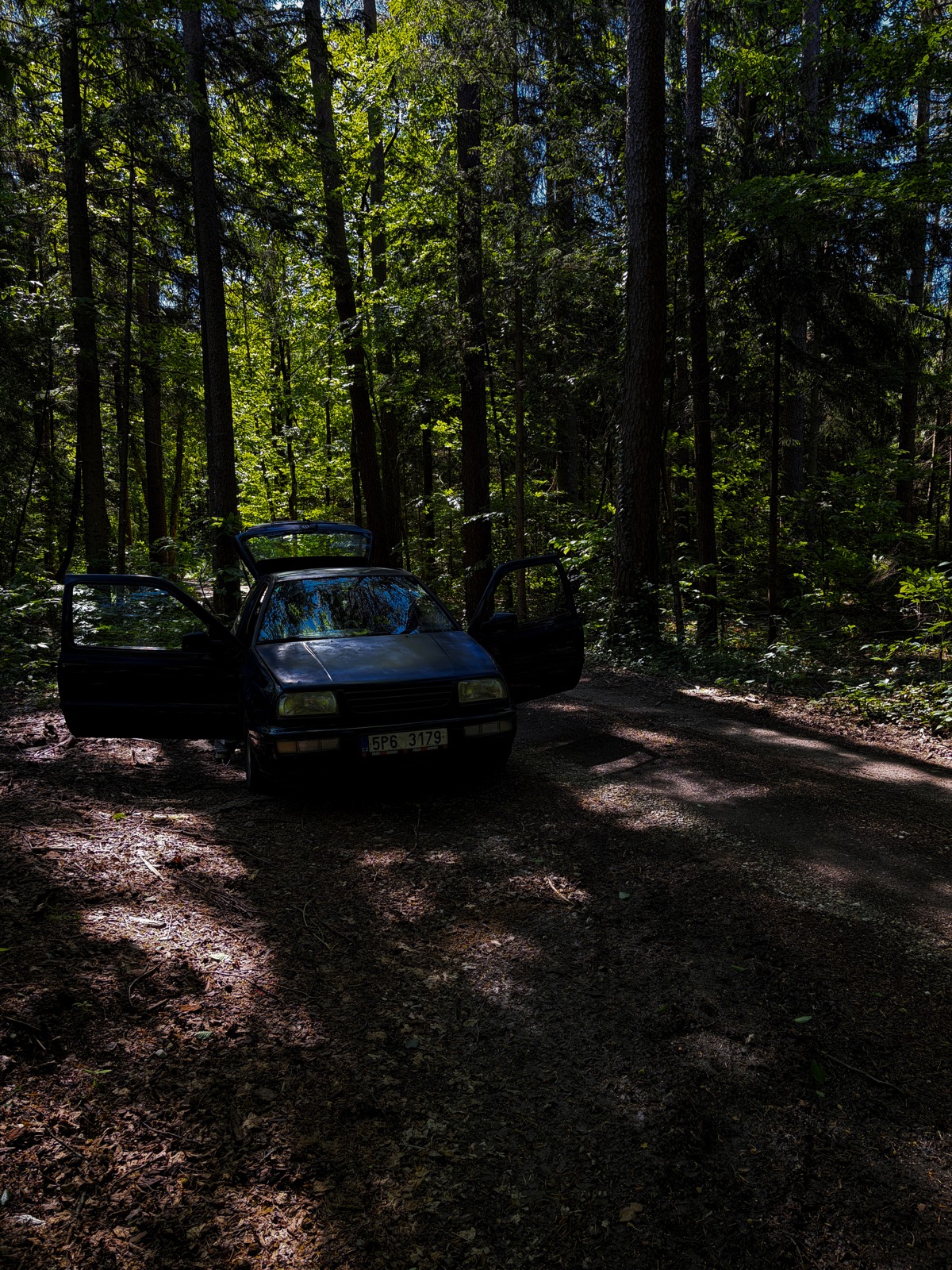 Golf MK3 s otevřenými dveřmi na lesní cestě, kde jsme přespávali